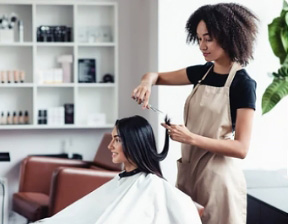 Professional hairstylist Professional hairstylist trims the ends of client’s hair at a salon